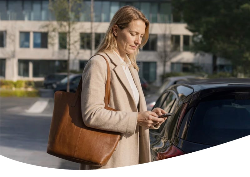 Onderneemster met telefoon bij haar auto van de zaak, met rittenregistratie volgens het Keurmerk RitRegistratieSystemen. Ga naar Naar de rekenhulp