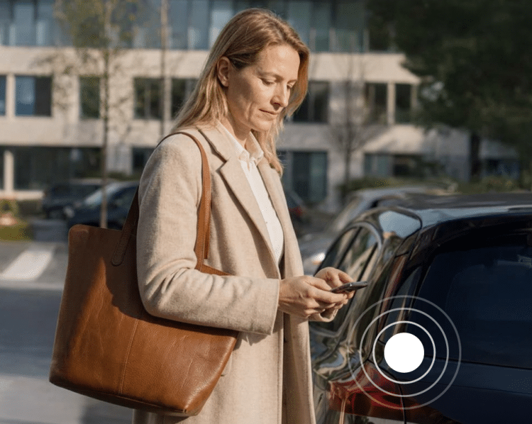 Vrouw met telefoon bij haar eigen auto voor een kantoorgebouw. Ga naar Zakelijke kilometers declareren