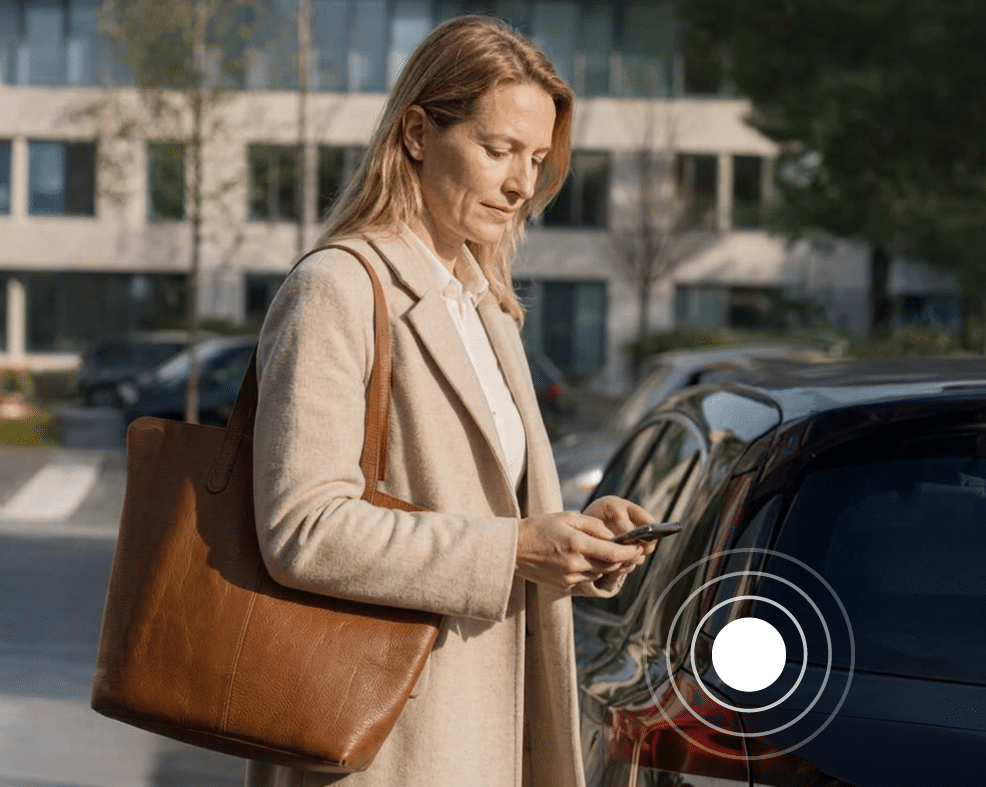 Vrouw met telefoon bij haar eigen auto voor een kantoorgebouw